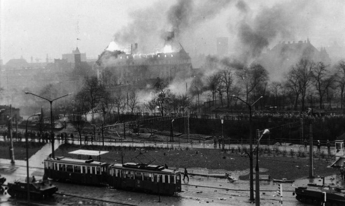 W oddali płonący budynek KW PZPR w Gdańsku. Na pierwszym planie transportery opancerzone stojące na ul. 3 Maja. 15 grudnia 1970 roku