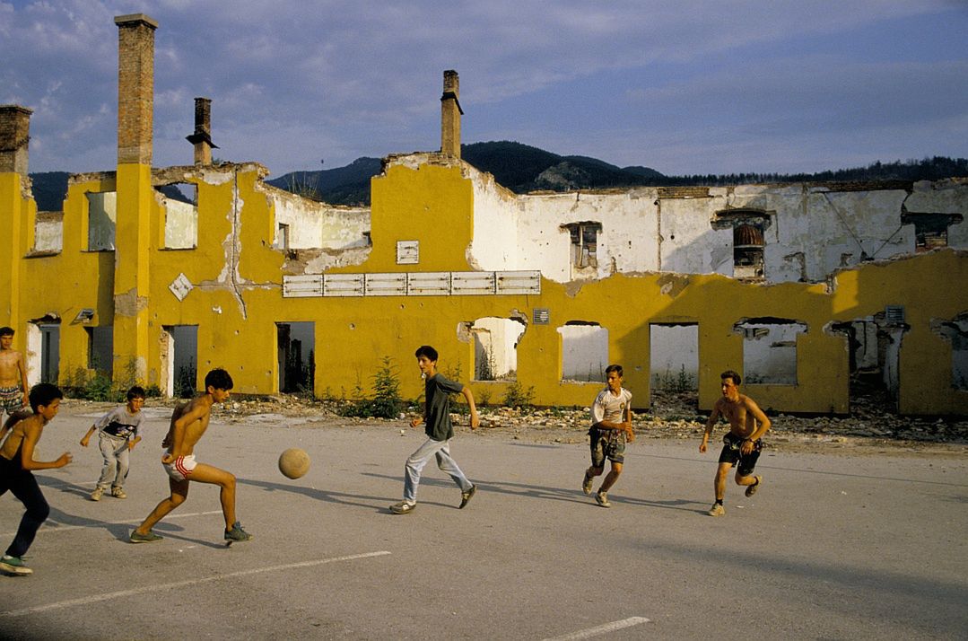 Grupa chłopców gra w piłkę w zniszczonym wojną Sarajewie, 1994 rok